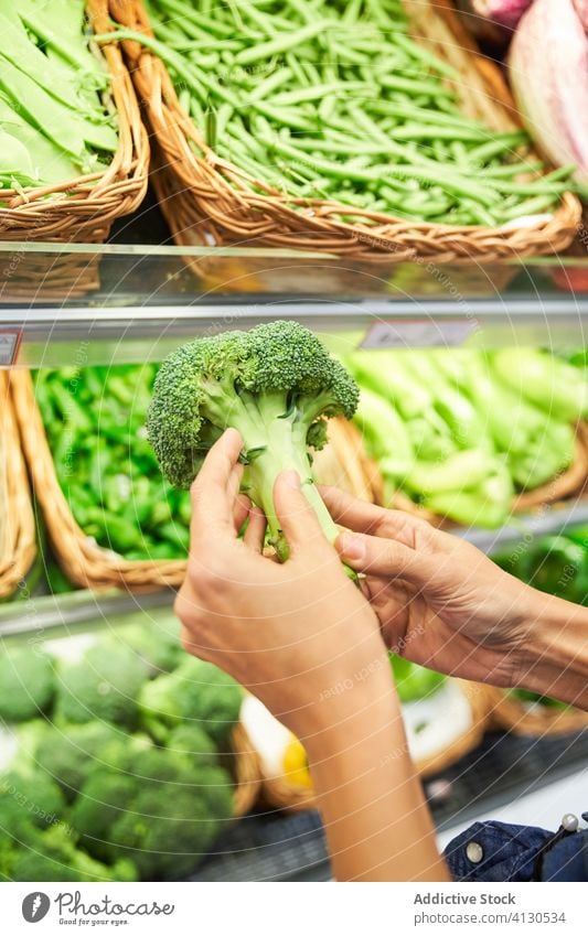 Female hand with broccoli in her hand in a fruit shop food vegetable diet healthy food fat guy eating top supplements green raw nobody fat eating shot studio