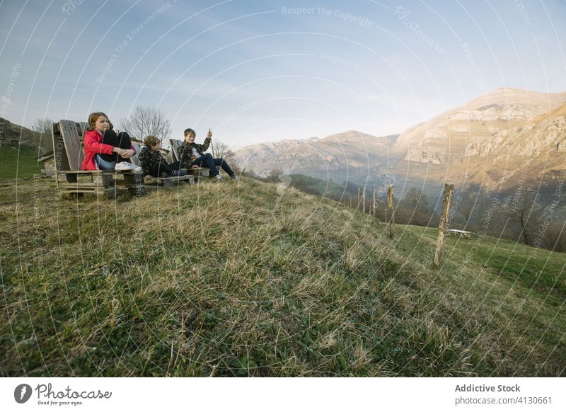 Group of children sitting on wooden benches on hill and enjoying view in Cantabria tourism together kid nature observe spain cantabria countryside green relax