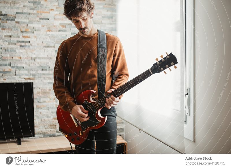 Man playing guitar at home man room cozy electric music apartment hobby male adult instrument casual song musician sound melody practice perform talent guy tune