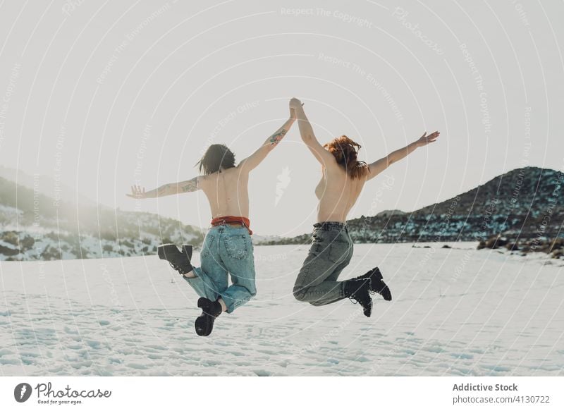 Happy topless women jumping in snowy field happy girlfriend carefree freedom enjoy together couple winter nature energy female fun countryside cheerful young