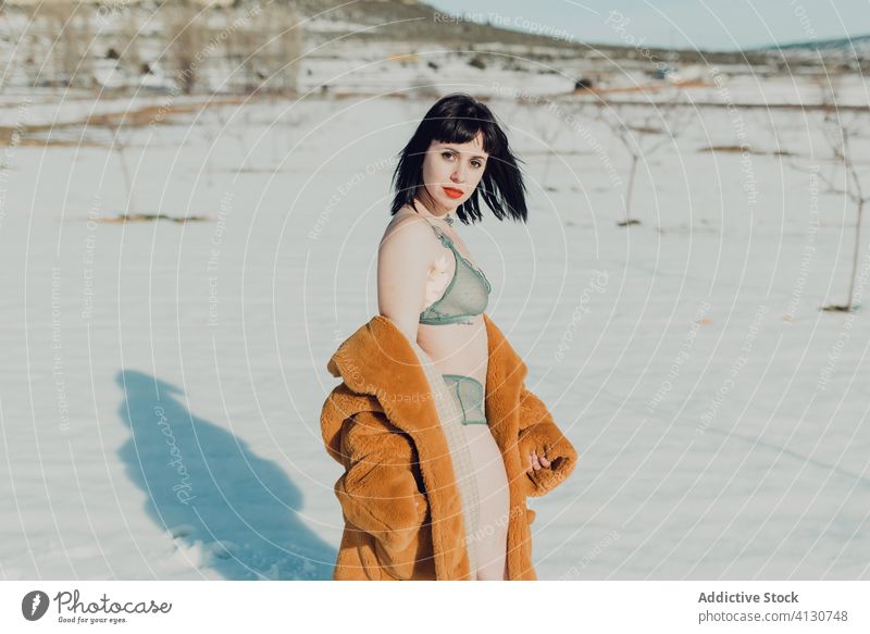 Young woman in fur coat and lingerie standing in snowy field sensual nature winter brunette confident female trendy young slim style fashion lady attractive
