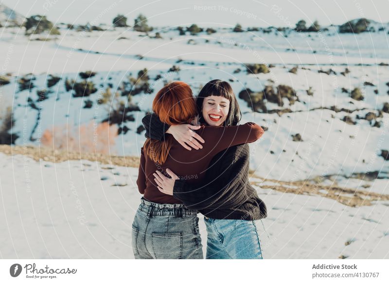 Happy women hugging in snowy field embrace happy friend cheerful together winter nature countryside casual girlfriend smile joy relationship love fun female