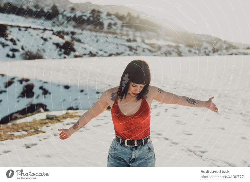 Carefree woman on snowy field in sunshine carefree relax freedom enjoy winter nature trendy female fun casual countryside young active adventure positive red