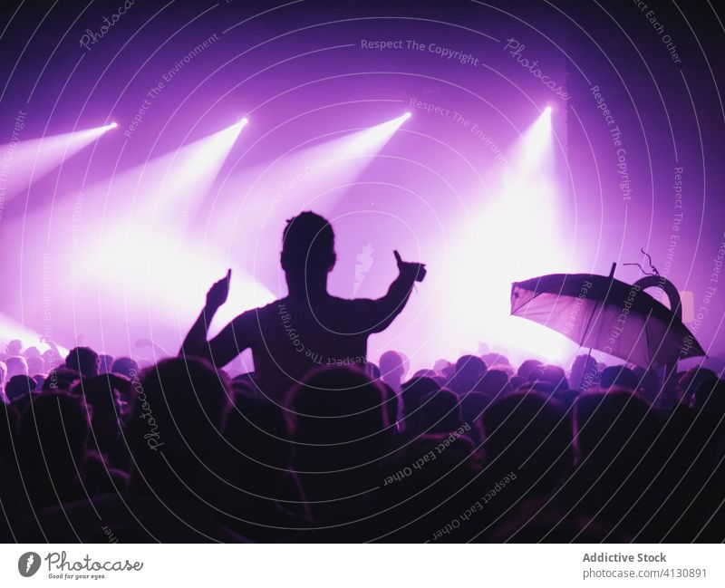 People with raised arms during show concert perform crowd people audience arms raised silhouette stage illuminate purple neon music event entertain light night