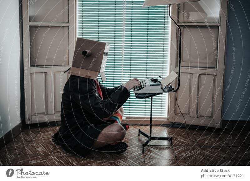 Anonymous male writer typing on old fashioned typewriter cardboard box man retro funny author story vintage antique carton creative eccentric stripe sock style