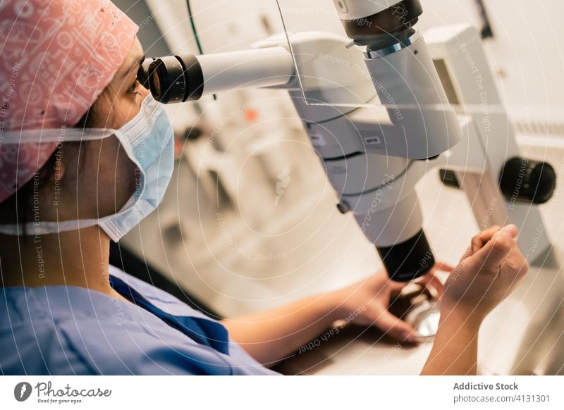 Woman in medical mask examining ovum through microscope woman doctor examine petri dish laboratory clinic inject uniform egg cell embryo modern medicine
