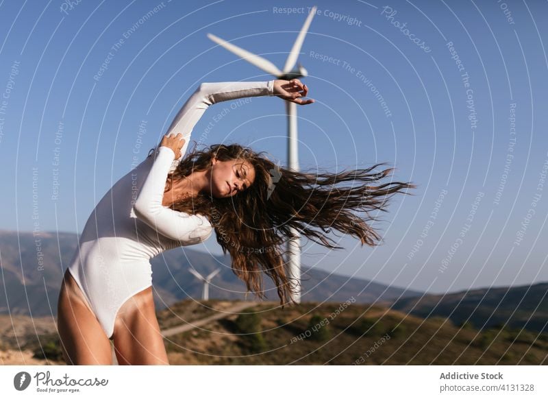 Flexible young lady dancing alone in nature with windmills woman dance harmony ecology environment sensual tender summer sustainable energy alternative power