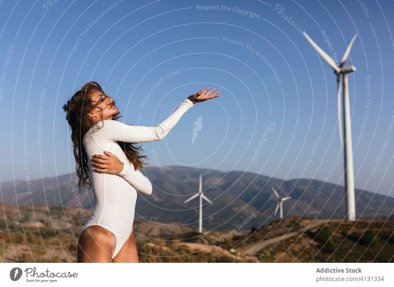 Tender female dancing alone near wind farm on sunny field woman dance countryside sensual nature ecology slim style alternative windmill energy move model