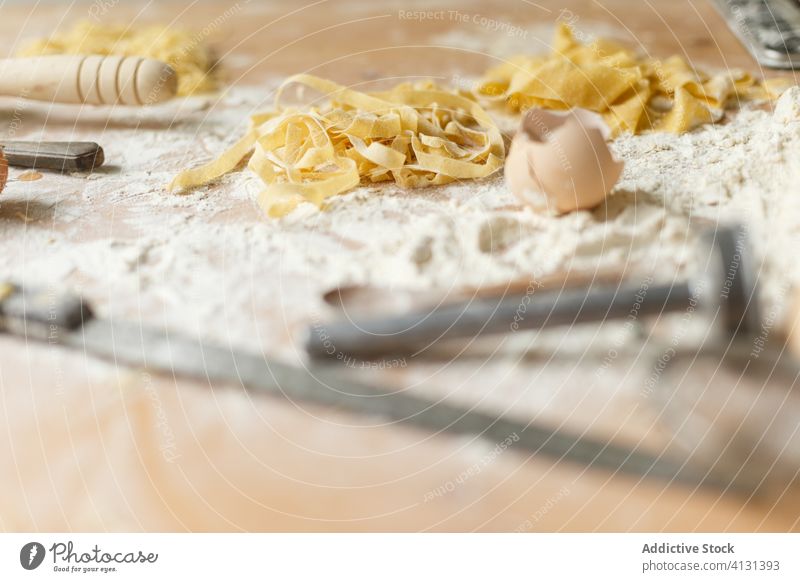 Messy table with pasta ingredients and cooking accessories on flour raw homemade messy eggshell kitchenware utensil cookery prepare disposable shape dirty glass