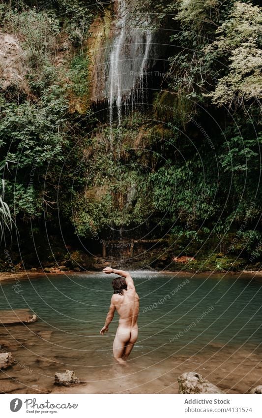 Man taking bath in waterfall pool forest man naked refresh small tropical plant stream jungle male travel tourism nature environment recreation wash nude