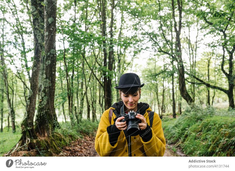 Stylish female photographer in forest woods take photo woman trendy path nature green creative asturias spain photography photo camera vacation hobby summer