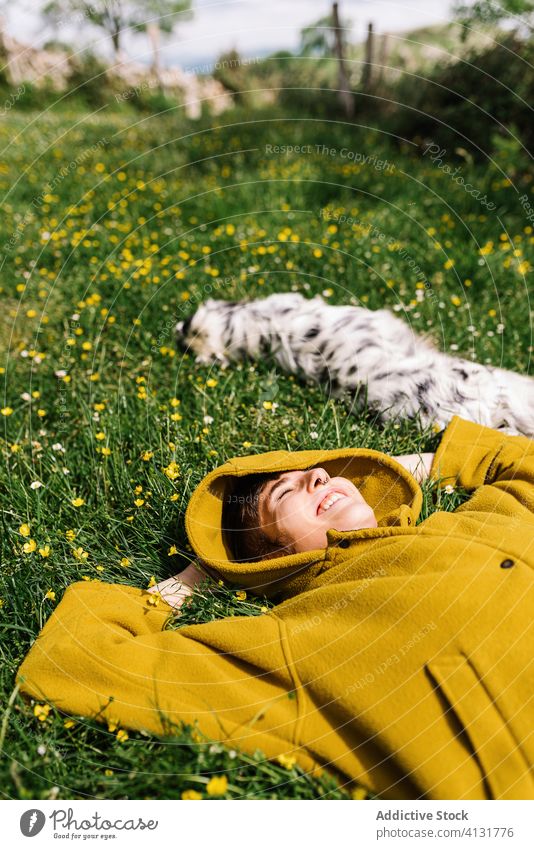 Cheerful woman with dog on meadow enjoy sun together lying cheerful flower content female asturias spain canine nature happy animal pet summer domestic