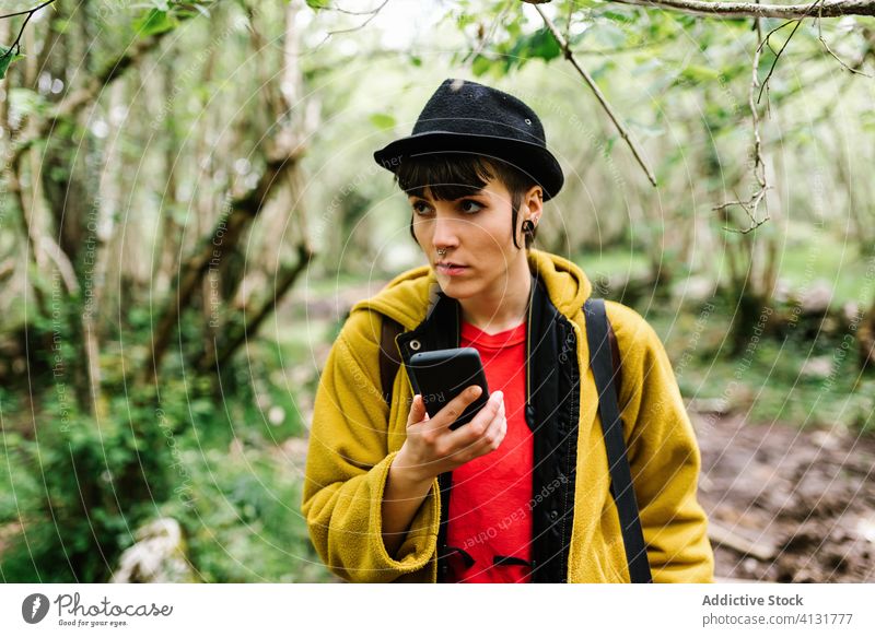 Calm androgynous female traveler using smartphone in forest woman green nature woods cellphone asturias spain holiday tourist tranquil summer mobile gadget