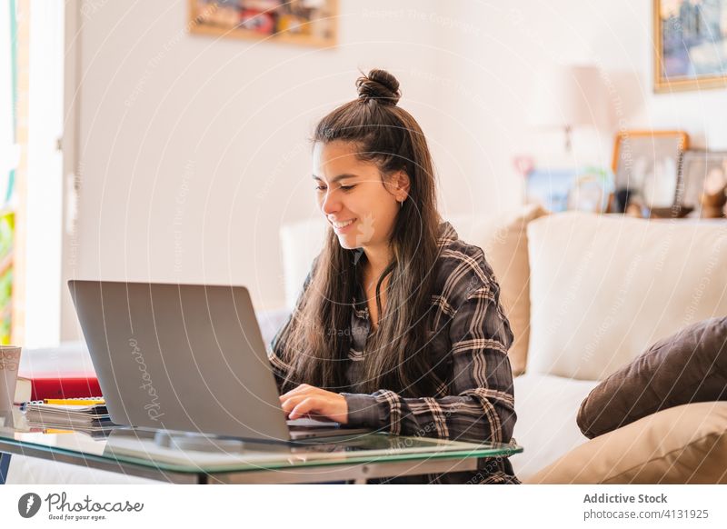 Young woman working with laptop in living room home using freelance sofa young casual remote female device gadget browsing internet lifestyle online couch focus