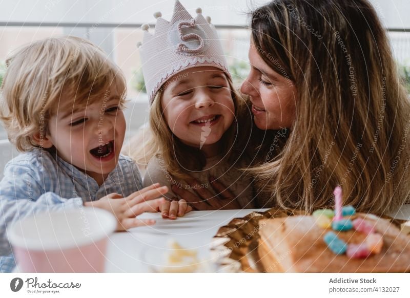 Happy mother and boy having birthday party girl brother celebrate kiss happy together son little excited home kid table positive parent child event love fun