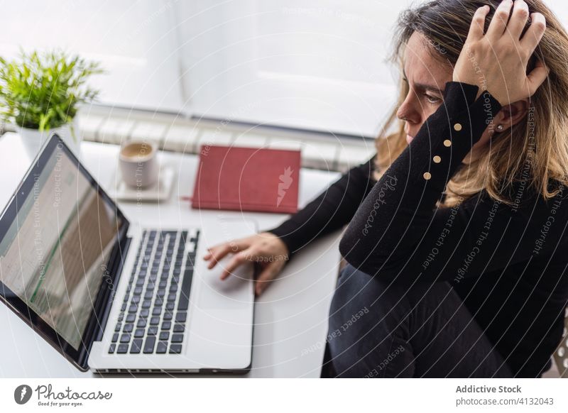Remote employee working with laptop at home woman using online remote busy casual serious table electronic internet connection read female workplace freelance