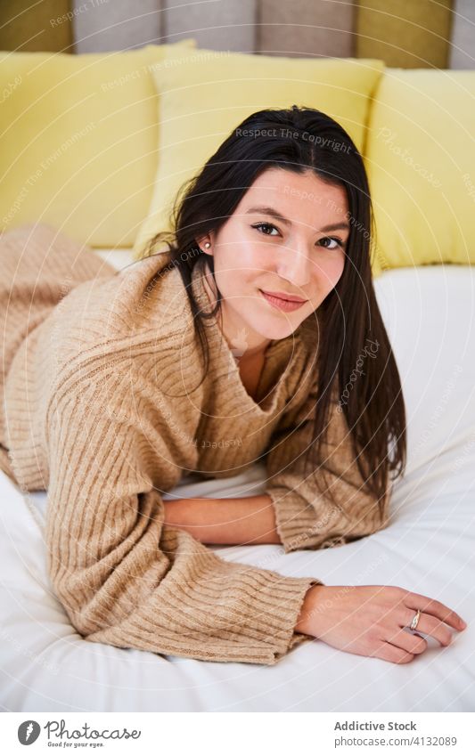 Carefree woman chilling on bed at home soft charming relax bedroom comfort cozy lying female oversize sweater modern rest cheerful style stockings serene warm