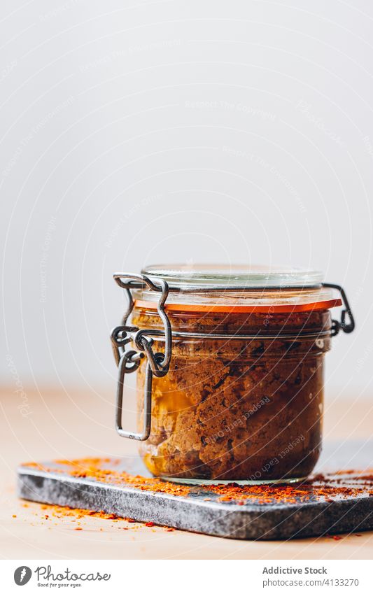 Red pesto in a jar red dried dehydrated tomatoes paprika peppers garlic cloves thyme rosemary olive oil glass pot hermetic raw ingredients uncooked mixture