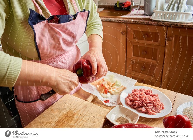 Anonymous housewife preparing pepper for cooking stuffed peppers woman kitchen elderly food prepare process cut female ingredient fresh vegetable apron dinner