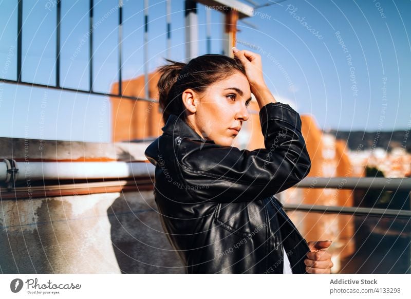 Calm stylish woman on balcony in summer trendy serene enjoy sun style leather jacket terrace female sunny relax rest tranquil calm harmony stand side view