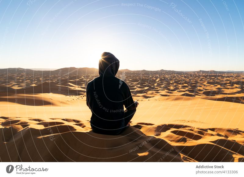 Unrecognizable traveler relaxing on sand in desert during sundown dune sunset admire tourist majestic landscape scenery morocco africa journey trip tourism