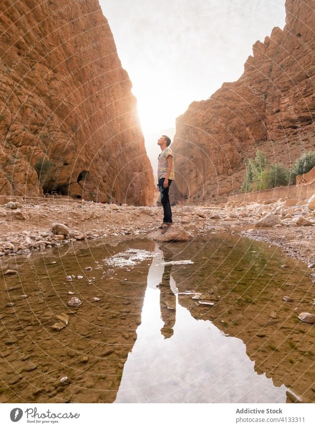 Male traveler in canyon near water cliff man admire stone rough mountain amazing male morocco africa tourist nature journey tourism adventure vacation