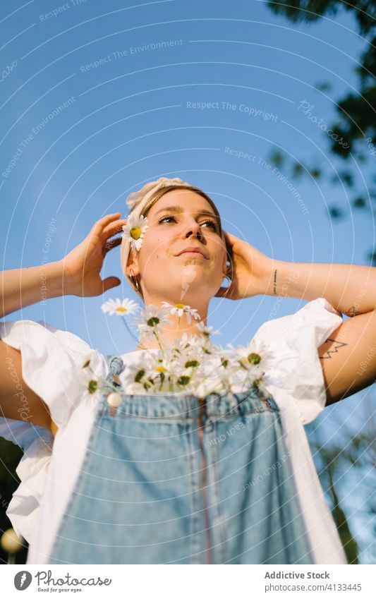 Young female with flowers standing in a meadow woman bouquet thoughtful fresh freedom happy summer enjoy pensive spread arms arms raised chest chamomile field