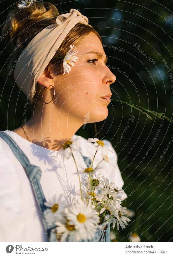 Young female with flowers standing in a meadow woman bouquet thoughtful fresh freedom summer enjoy pensive chest chamomile field nature sunny day green daisy