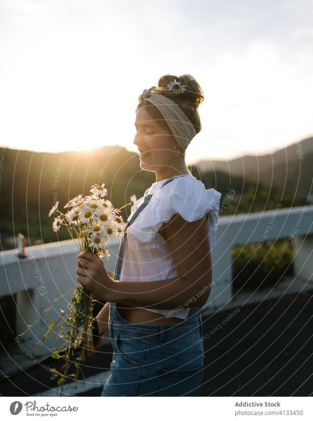 Happy young lady with bouquet of fresh chamomile on balcony woman sunset summer happy calm terrace carefree sunny flower bloom walk cheerful nature smile