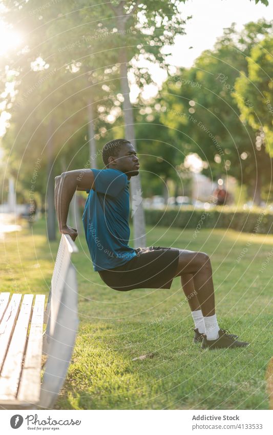 Athletic black man exercising at the park male fitness workout sport runner warming up flexibility healthy lifestyle stretching athlete young training body