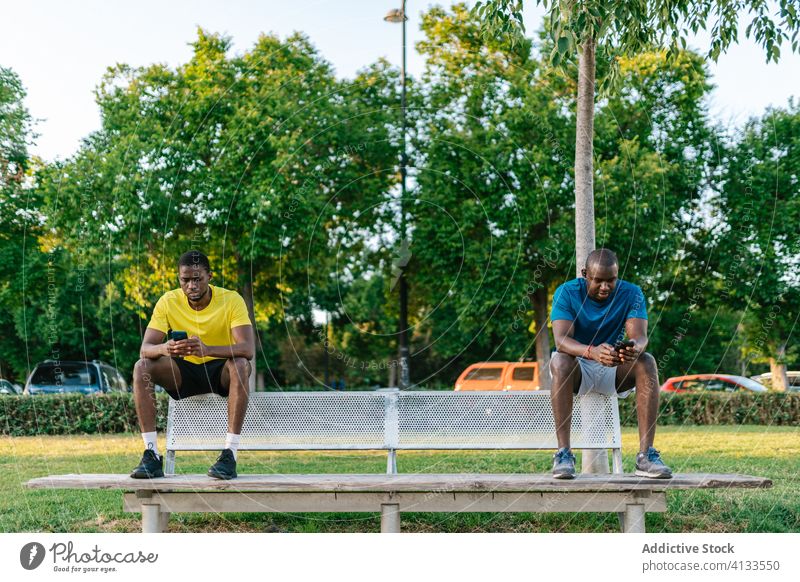 Social distancing in the park social distancing black men technology phone sitting selfie lifestyle break communication rest resting adult african coronavirus