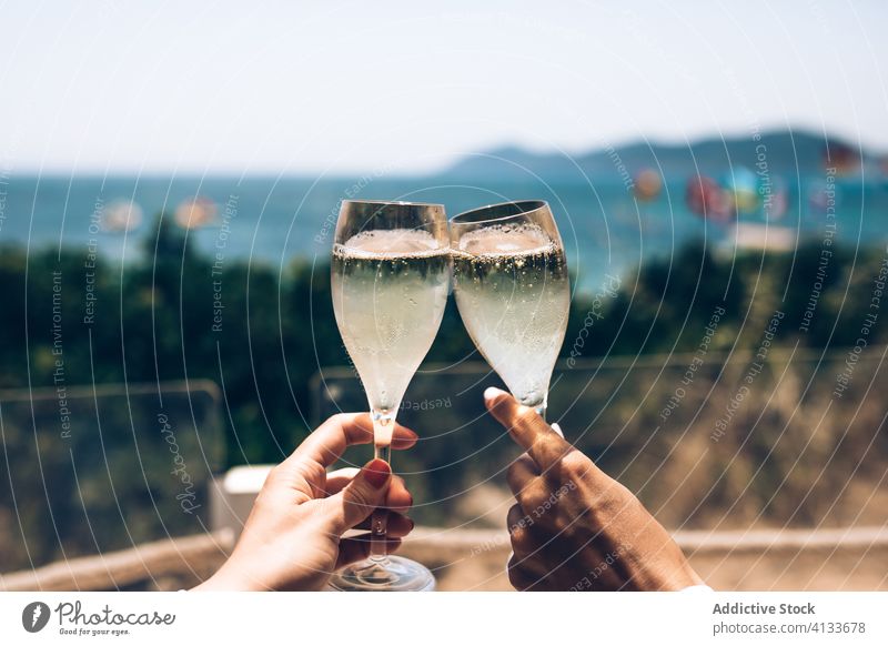 Couple clinking champagne glasses at seaside couple cheers summer together celebrate enjoy holiday drink vacation relationship romantic alcohol love relax beach