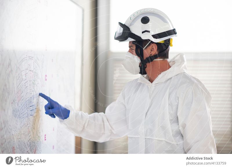 Male firefighter in protective uniform reading city map fireman fire station paper navigate respirator coronavirus male costume stand direction safety helmet