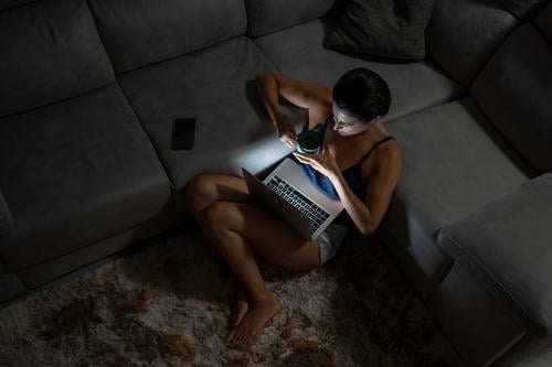 Content woman using computer in living room home evening content laptop coffee female cup domestic carpet technology browsing gadget internet connection cozy