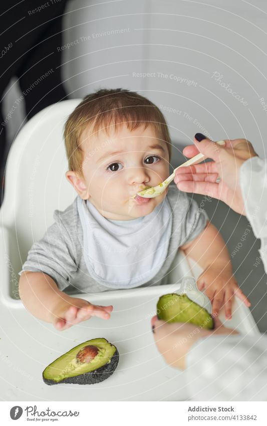 Mother feeding little kid with avocado baby eat mother food toddler fresh healthy natural meal child cute childhood hungry nutrition care tasty delicious diet