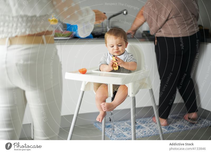 Little baby sitting in high chair and examining avocado eat food kitchen home toddler focused examine child cute meal table kid childhood little concentrate