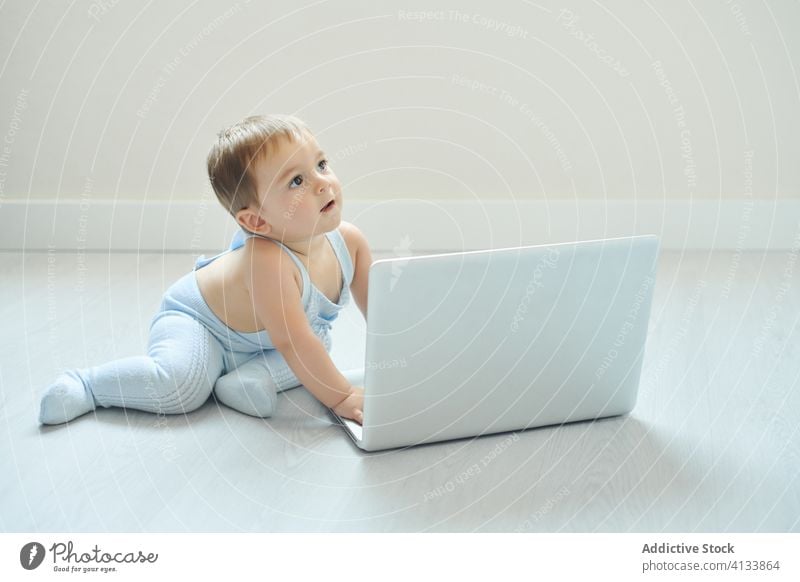 Cheerful baby playing with laptop at home happy using toddler gadget modern childhood lifestyle little alone kid cheerful device netbook cute innocent excited