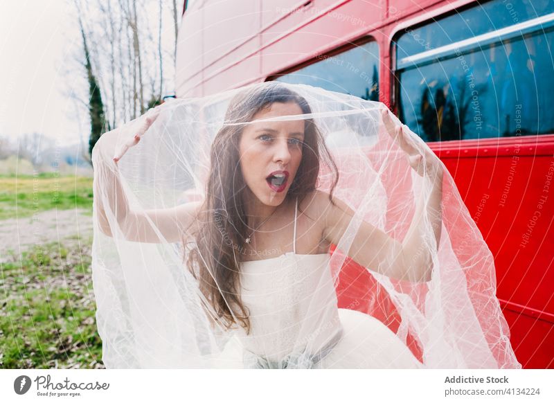 Amazed bride covering face with veil cover face newlywed amazed double decker wedding dress red bus surprise female elegant wood retro forest wedding day