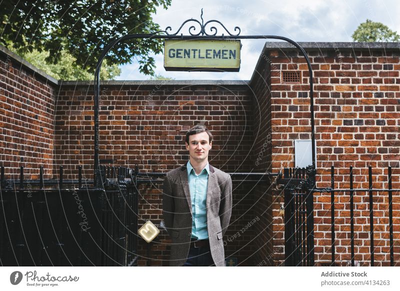 Content man in elegant jacket on street classy gentleman smile signboard building brick wc public male london england united kingdom outfit inscription stand