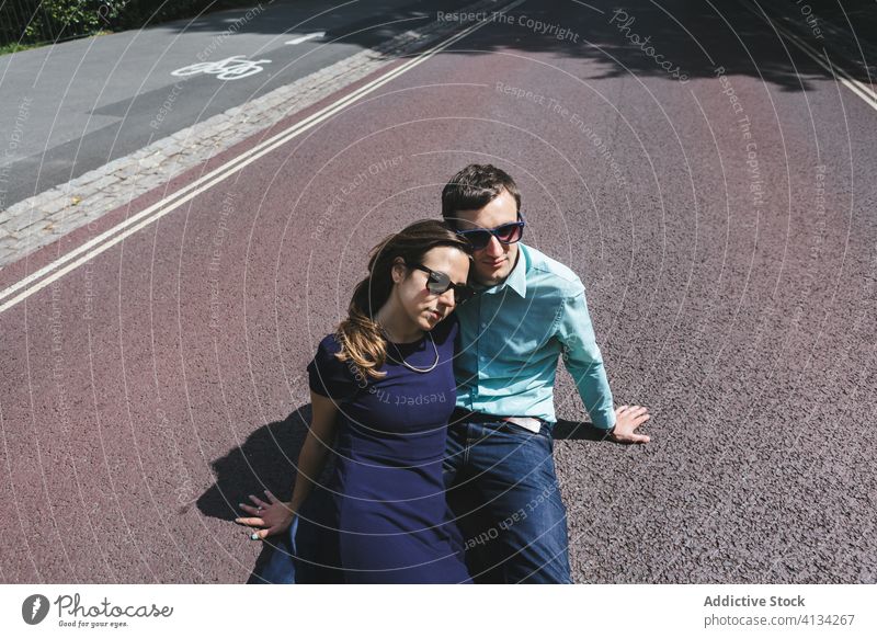 Unemotional couple lying on asphalt road in city sitting eccentric style unemotional chill roadway london england united kingdom relax relationship weekend