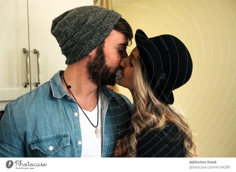Happy couple embracing while drinking coffee at home kiss relationship positive hipster style boyfriend affection fondness together embrace kitchen love