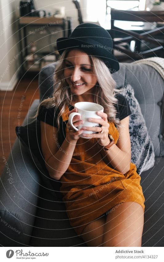 Happy young woman with cup of coffee sitting on chair smile home style comfort confident rest pleasant calm slim tranquil cheerful optimist enjoy glad happy