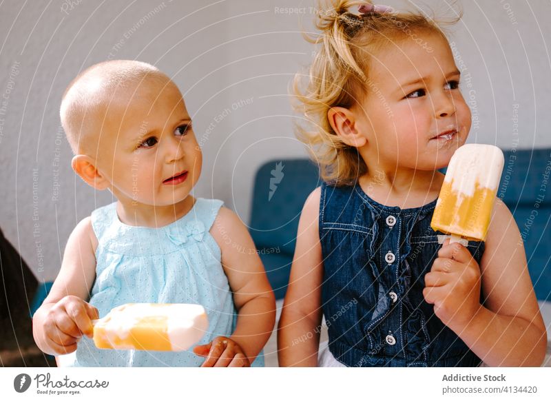 Content sisters eating homemade ice lollies on terrace popsicle lolly girl kid together yummy toddler little delicious sweet cute courtyard tasty dessert