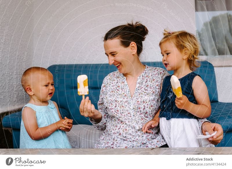 Delighted grandmother and little girls eating ice cream on terrace popsicle enjoy granddaughter together courtyard homemade delight woman cheerful toddler smile