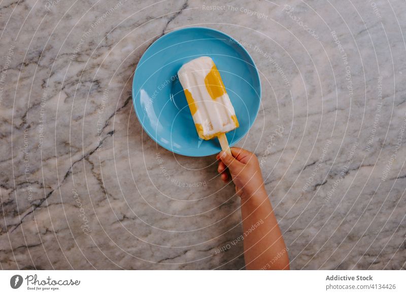 Anonymous kid grabbing homemade ice lolly on plate popsicle stick ice cream delicious summer treat dessert sweet fresh food tasty table marble hands gourmet