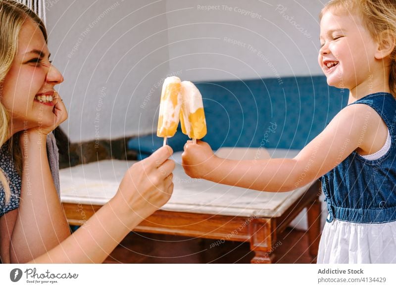 Smiling mother and daughter with ice lollies on terrace popsicle lolly enjoy summer girl smile cold homemade ice cream little woman cheerful together courtyard