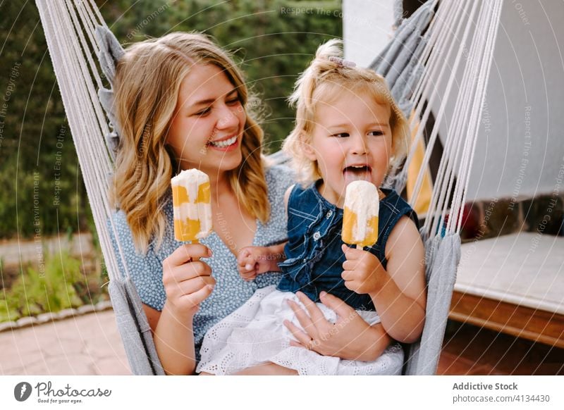 Happy little girl and woman with homemade popsicles mother daughter hug lolly ice enjoy cheerful summer terrace smile ice cream toddler female together