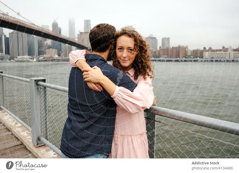 Happy couple embracing on embankment embrace promenade stroll city relationship river hug brooklyn bridge new york america united states usa wooden smile