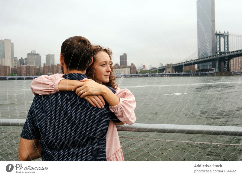 Happy couple embracing on embankment embrace promenade stroll city relationship river hug brooklyn bridge new york america united states usa wooden smile