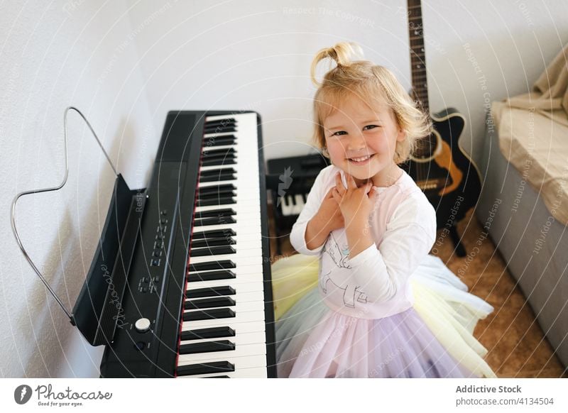 Cute girl learning to play modern piano home synthesizer study childhood cute music happy smile class skirt schoolgirl education practice prepare little
